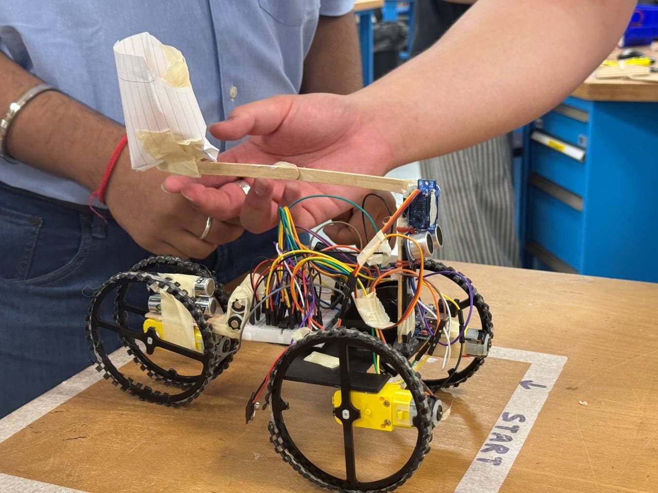 The finished robot held up on the course table, with the ball holder raised